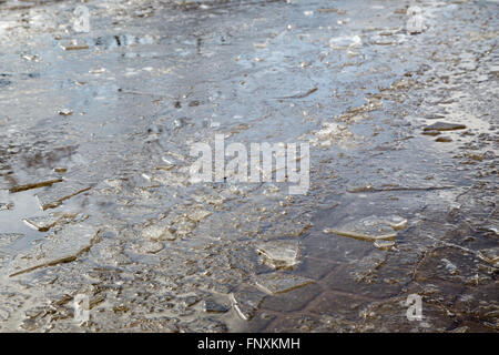 Puddles and chopped ice on the sidewalk in the spring. Stock Photo