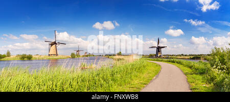 A path along traditional Dutch windmills on a bright and sunny day at the Kinderdijk in The Netherlands. Stock Photo