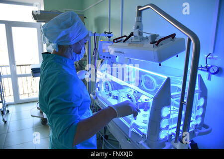 A nurse in hospital near the Incubator in which lies a newborn baby. Stock Photo