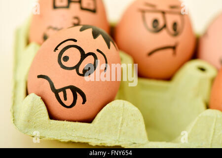 closeup of some brown eggs ornamented with funny faces in an egg carton Stock Photo