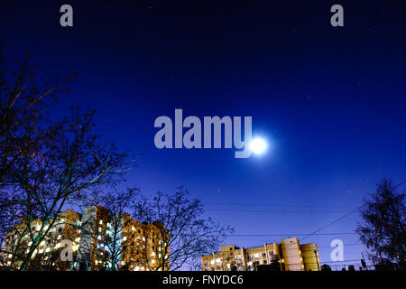 The starry sky and the moon over the buildings. View from my window. Moon and star dust in the sky. Stock Photo