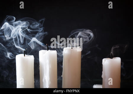 Few extinguished candles in a row on dark background Stock Photo
