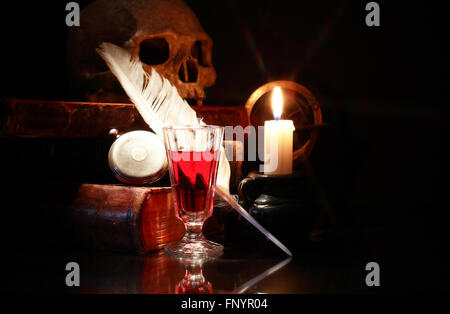 Medieval still life. Old books and quill near wine and lighting candle Stock Photo