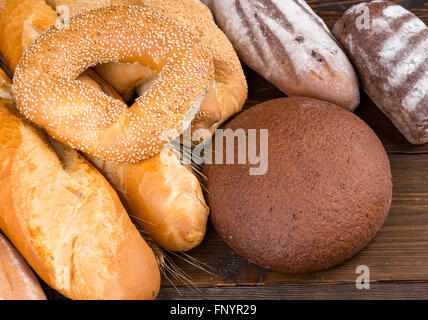 Set of breads with examples of sesame seed bagels, baguettes, rolls and artisan loaves on dark wood table Stock Photo
