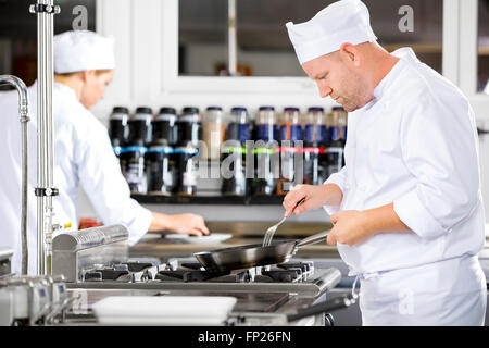 Focused chefs makes food in professional kitchen Stock Photo