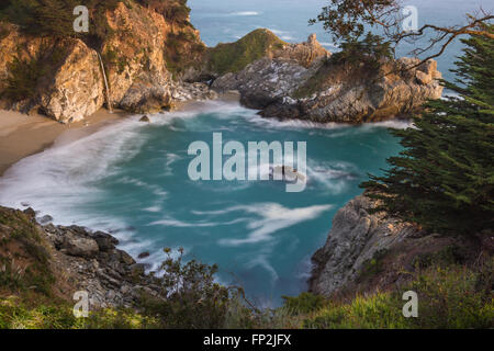 Waterfall in Julia Pfeifer Burns State Park at sunset with a soft golden color on the rocks Stock Photo