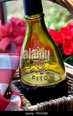 Bottle of Languedoc Fitou red wine in rustic wicker wine carrier in floral alfresco picnic situation Aude Southern France Stock Photo