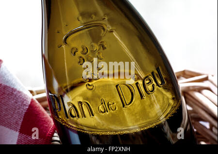 Close view glass relief label Plan de Dieu (God’s Plain) Côtes du Rhône red wine in wicker basket Stock Photo