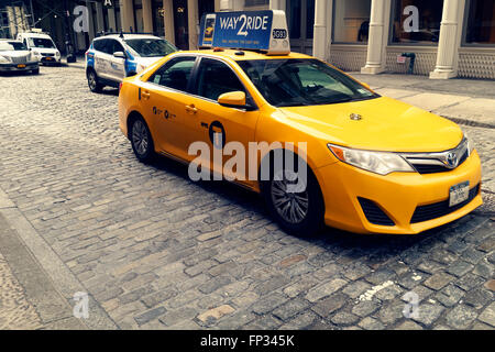 Taxi cab on cobblestone street in the Soho are in New York City. Stock Photo