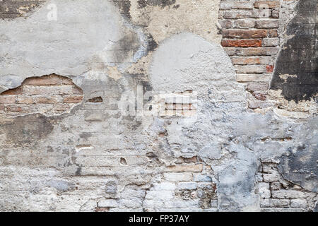 Old brick wall with damaged stucco and paint layers, closeup background photo texture Stock Photo