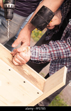 Wooden birdhouse is under construction, carpenters work with rubber hummer and drill Stock Photo