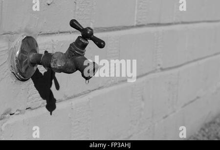 old exterior Dripping Faucet in black and white Stock Photo