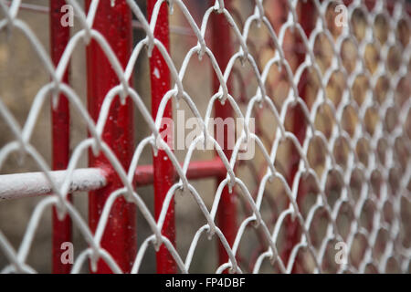 Close up of white and red metal chain fence, barrier on the side of railway path Stock Photo