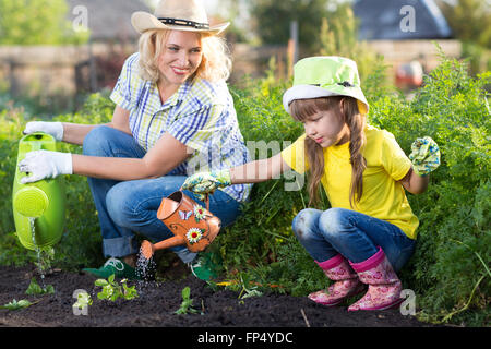 Mother and daughter watering plants in garden. Stock Photo
