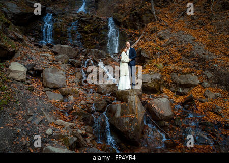 Romantic wedding couple. Waterfall on background. Honeymoon in the mountains Stock Photo