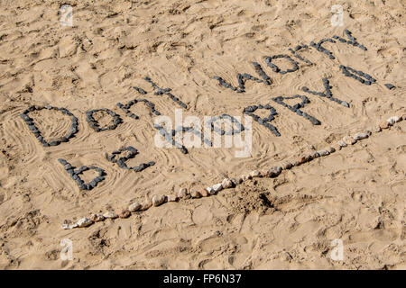 Don't Worry Be Happy, with stones in sand. Stock Photo
