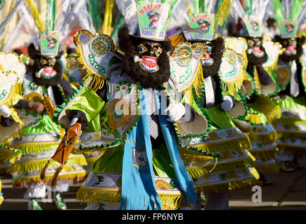 'Los Fanaticos'. The famous 'negritos', dancers dressed in black wool masks dancing at the Festival honoring Virgen del Rosario, Chucuito Province, Puno Region, Peru. The  Virgen del Rosario is the patron saint of the Dominican Order, who were in charge of the slave brotherhoods in colonial times. The celebration is highlighted by the presence of pallas, ladies dressed in costumes with wide sleeves and tall crowns of flowers, and the famous negritos, dancers dressed in black wool masks who liven up the celebration. Stock Photo