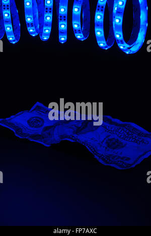 Blue led strip with crumpled 100 dollar bill on the black background Stock Photo