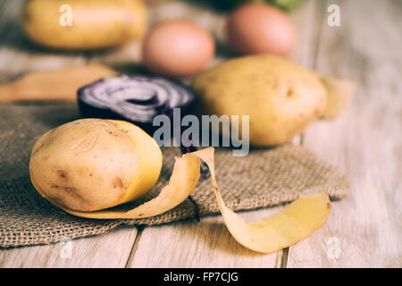 closeup of some potatoes, a half raw red onion and some brown chicken eggs, to prepare a spanish omelet or some other recipe, on Stock Photo