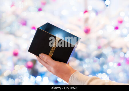 Woman opens a black box gift in front of a Christmas tree Stock Photo