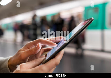 Woman using her mobile phone on platform subway station. App, sms, message, mail, texting Stock Photo