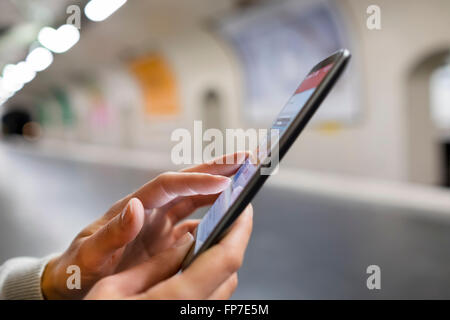 Woman using her mobile phone on empty platform subway station. App, sms, message, mail, texting Stock Photo
