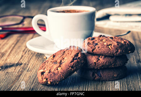 Cup of coffee with biscuit cookies and newspapper. Chocolate biscuit cookies. Chocolate cookies on wooden table. Stock Photo