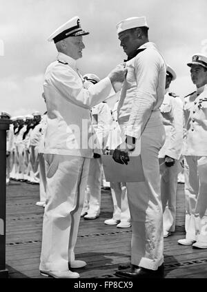 Admiral Chester W. Nimitz, Commander-in-Chief, Pacific Fleet, pinning the Navy Cross on Doris 'Dorie' Miller, Steward's Mate 1/c, at a ceremony on board a U.S. Navy warship in Pearl Harbor, on May 27, 1942. Miller got the Navy Cross for his bravery during the attack on Pearl Harbor on December 7, 1941 and was the first black American to receive the award. Official US Navy Photo. Stock Photo