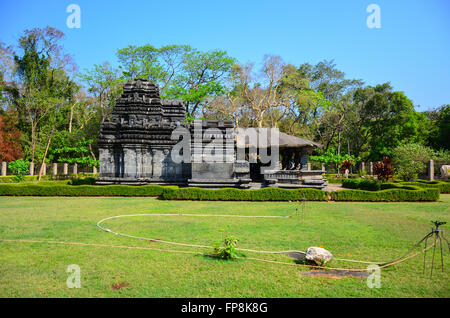 The ancient Mahadev Temple built of basalt amidst well maintained lawn, trees and blue sky at Tambdi Surla, Sanguem, Goa, India Stock Photo