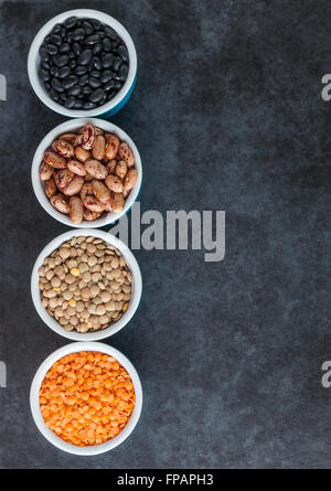 Red and brown lentils, heirloom beans, and black turtle beans on dark grungy surface. Top view with copy space. Stock Photo