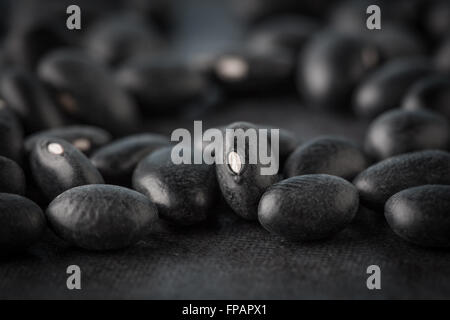 Black turtle beans on dark surface extreme closeup. Shallow depth of field. Stock Photo