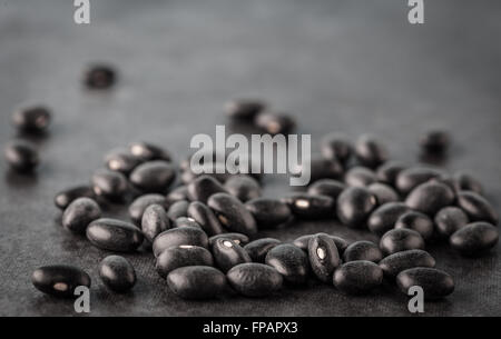 Black turtle beans on dark surface extreme closeup with copy space. Shallow depth of field. Stock Photo