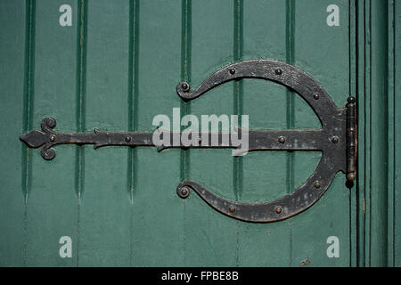 Closeup of ornate hinge with peeling paint on old green door Stock Photo