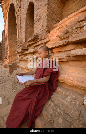 A young monk reading in the temples of Bagan, Myanmar Stock Photo