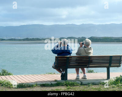Elderly Couple Using Binoculars to Look for Wildlife Stock Photo