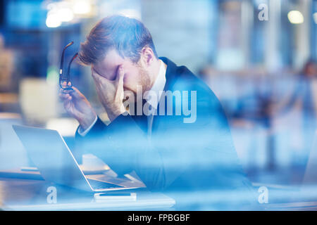 Depressed businessman sitting with laptop Stock Photo