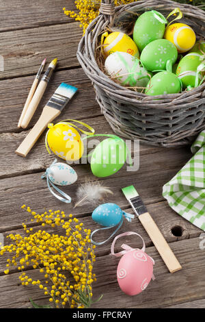 Colorful easter eggs and brushes on wooden table Stock Photo