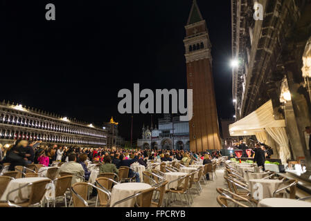 People listening to a small orchestra at an evening concert at the cafe 'Caffe Florian' on the St. Marks square in Venice Stock Photo