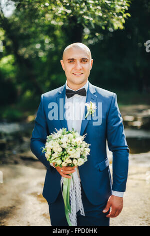 The groom in blue suit with butterfly and bouquet Stock Photo