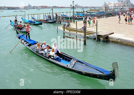 Venice gondola Italy leaving moorings with sightseeing passengers for tour around the cities canals Stock Photo