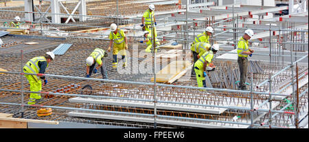 Construction site workers busy working together on fixing steel reinforcement for suspended concrete floor high rise apartment block London England UK Stock Photo