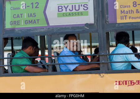 Indian men on a bus with no glass windows and bars across the opening travelling along the OMR in Kelambakkam Stock Photo