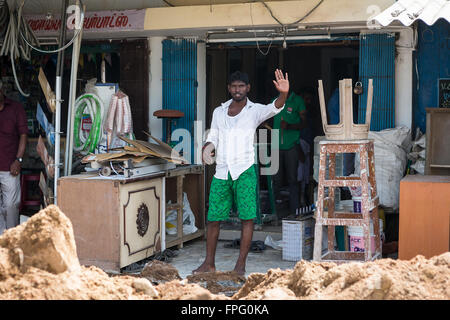 Indian man in shorts standing in a roadside shop in Maduranthakam, Kancheepuram district of Tamil Nadu and waving at the camera Stock Photo