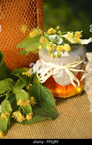 jars of fresh and delicious honey with linden flowers and honeycomb Stock Photo