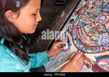 Nepal, Patan.  Young Woman Painting a Thangka, a Tibetan Buddhist Painting. Stock Photo