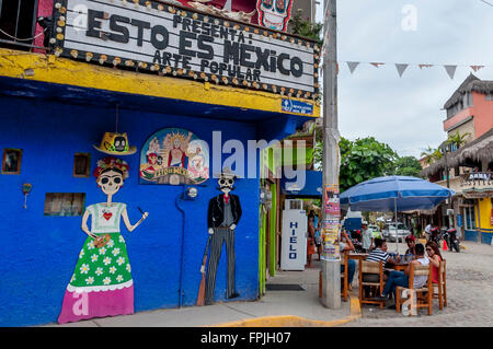 Street scene in Sayulita, Riviera Nayarit, Mexico, with 'Esto Es Mexico' art and gift shop and people visiting at table outside. Stock Photo