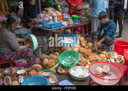 Hoi An,Vietnam Man and woman splitting and grating coconuts for sale.  Coconut  products are an important product locally Stock Photo