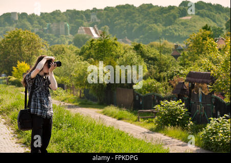 Man taking picture of town landscape during sightseeing, black dressed long hair young person holding the camera near his eye Stock Photo