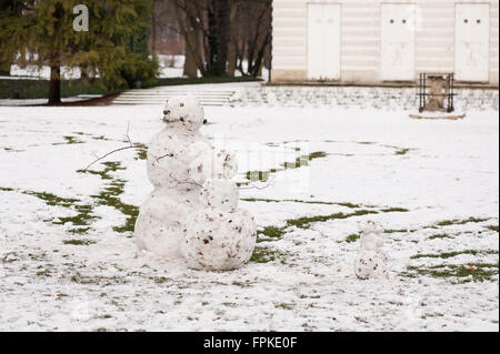 Snowmen family in park, two large and one little snowman in cold winter weather and fun season in horizontal orientation, nobody Stock Photo
