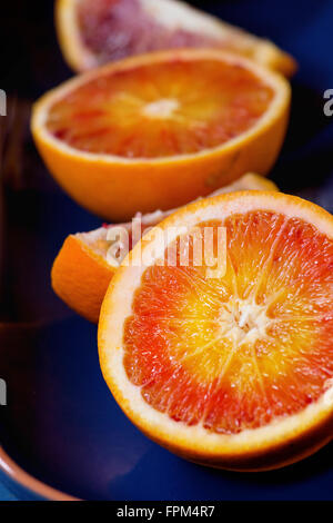 Close up of Sliced Sicilian Blood oranges fruits in blue ceramic plate. Stock Photo